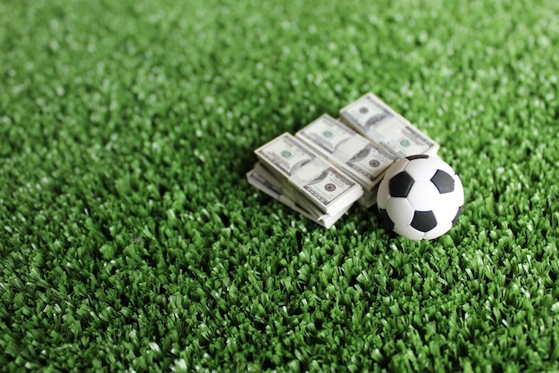 Selective focus image of soccer football and money on field Sport betting and bribery concept