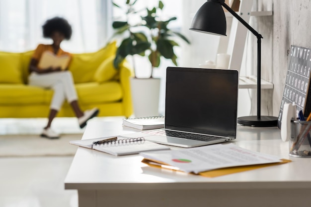 Selective focus of laptop on table and african american freelancer at home office