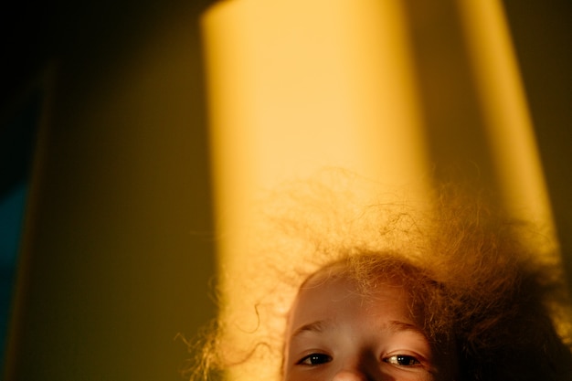 Selective focus. The little blonde cute girl plays hide and seek. Sunset warm light. Sunlight in hair. Summer happy time.