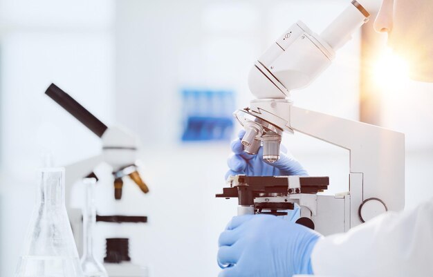 selective focus of male scientist looking through microscope in laboratory