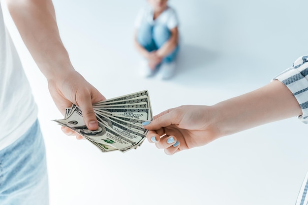 Selective focus of man giving alimony to woman near kid on white