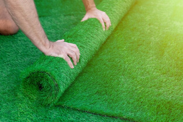 Photo selective focus on a man's hands unrolling an artificial turf easy laying of artificial green grass