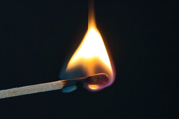 A selective focus of a match on fire on black background