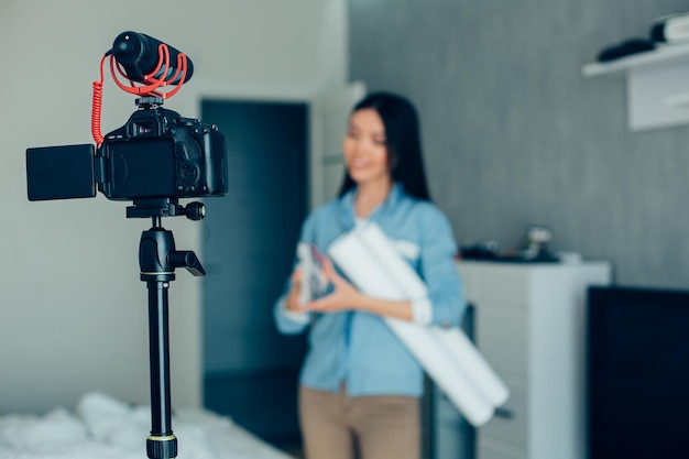 Selective focus of a modern camera on a tripod and a young woman recording herself at home Website banner