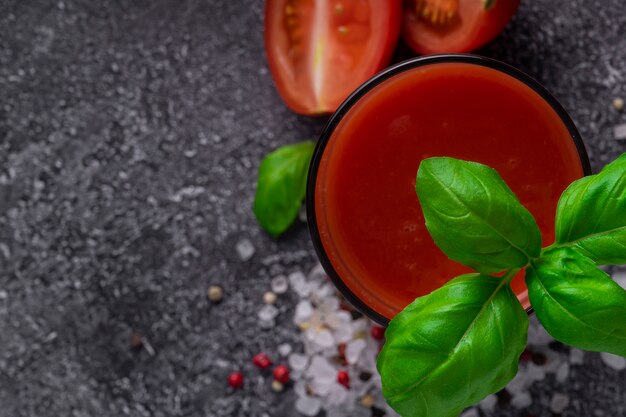 Selective focus, natural tomato drink, tomato juice with spices and a sprig of green Basil