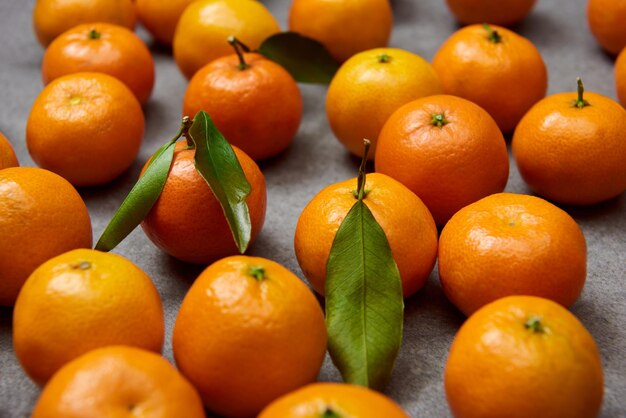 Selective focus of orange tangerines with green leaves on grey table