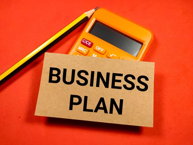 Selective focus of pencil and calculator with text BUSINESS PLAN on red backgroundBusiness concept