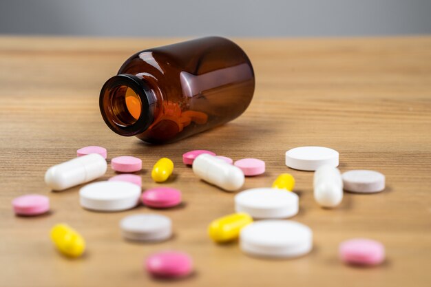 Selective focus on pill spread on wooden background. Global healthcare concept. Pharmaceutical industry. Drugs in medical container on wooden background.