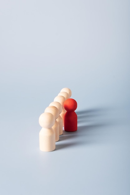 Selective focus on a red wooden figure that stands apart from other identical figures The concept of protest group assembly distinctive features of the individual