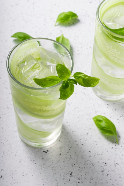 Selective focus, refreshing drink with sliced cucumber, in a tall glass with green Basil leaves