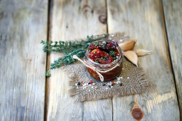 Selective focus. Sun-dried tomatoes in a jar with spices and garlic.