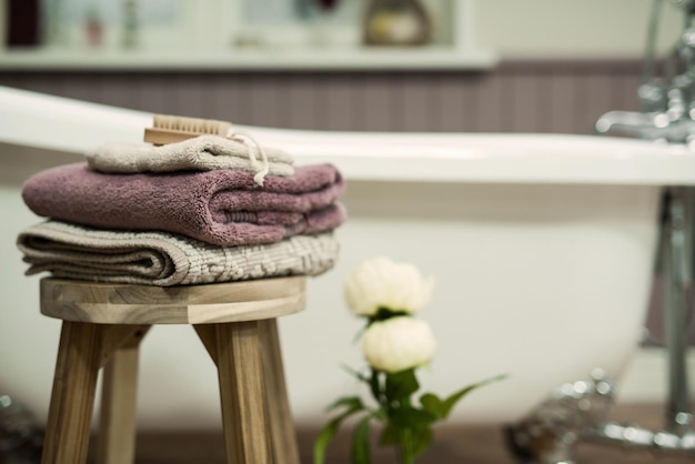 Selective focus of three  towels with a wooden brush on top on a wooden chair in the bathroom