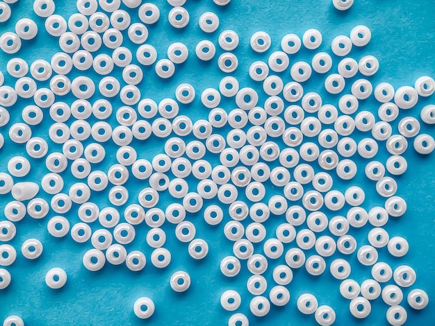 Selective focus white pearl beads for needlework on a blue background making jewelry from beads