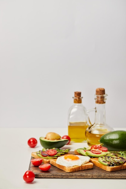 selective focus of wooden cutting board with toasts scrambled egg cherry tomatoes avocados and