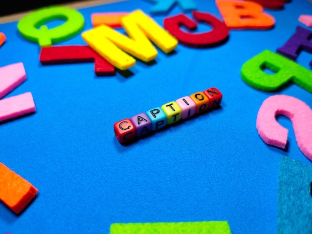 Selective focusColorful dice with word CAPTION on blue backgroundShot were noise and film grain