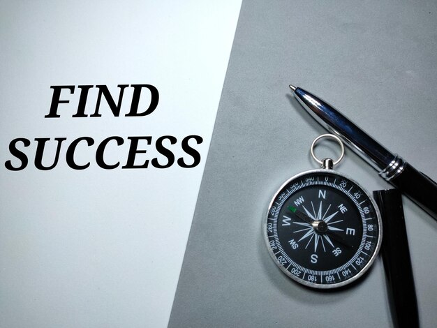 Selective focusCompass and pen with word FIND SUCCESS on a white and gray background