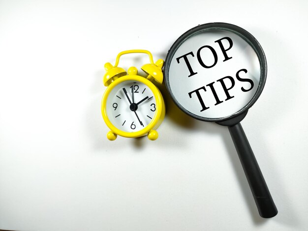 Photo selective focusword top tips with magnifying glass and clock on white backgroundbusiness concept