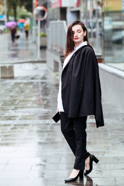 Self assured female director with red lips poses near office building