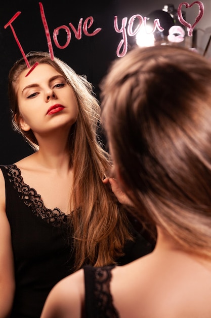 Self assured woman with red lips looking in mirror