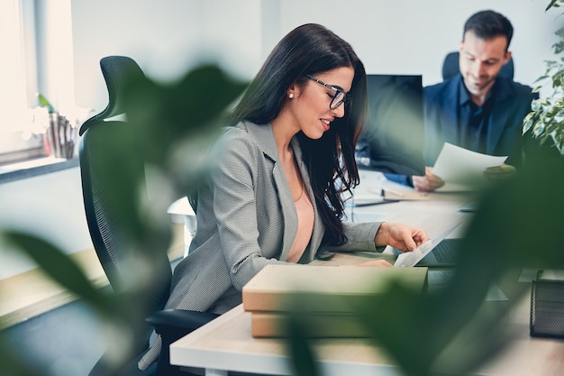 Self-confident female employer wearing glasses working at new office using modern computer