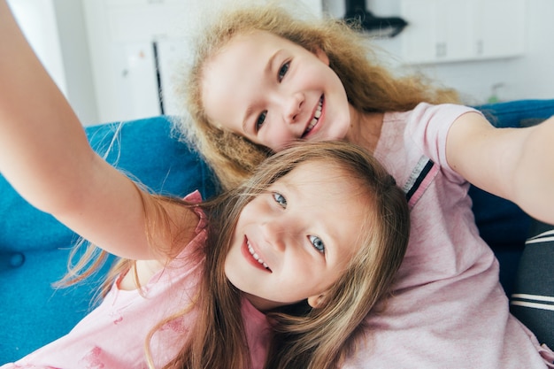 Self portrait of crazy, foolish sisters, laughing, together making selfie on mobile phone at home