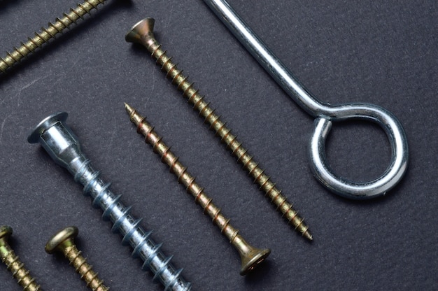 Self-tapping screws and various fittings are laid out on a dark surface