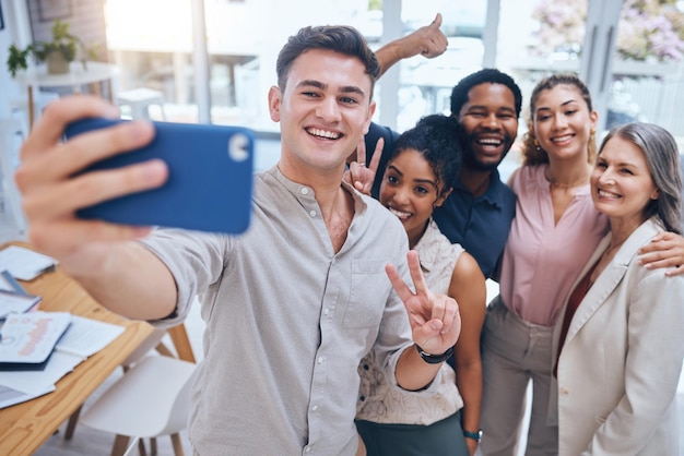 Selfie diversity and teamwork with happy business people showing peace sign in startup office Positive workplace and employee engagement for motivation with healthy staff in a fun work environment