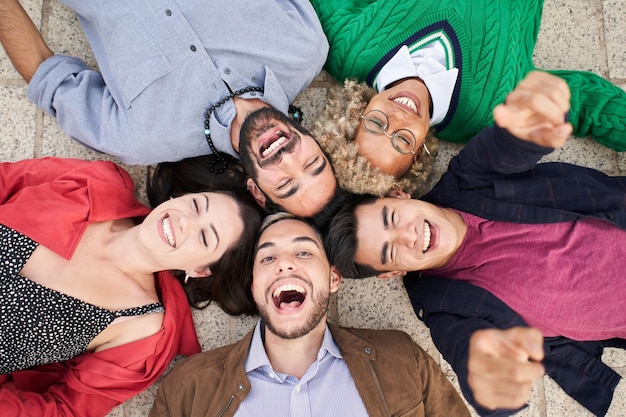 Selfie of a group of friends lying in a circle looking at the camera