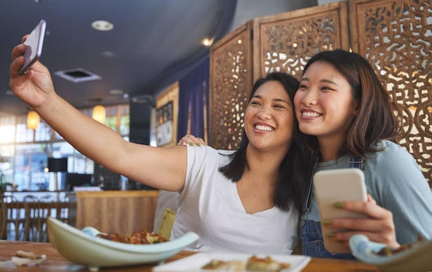 Selfie lgbt and a gay couple in an asian restaurant for a romantic date together on an anniversary Lesbian smile and happy asian woman with her partner in a cafe for eating or celebration of love