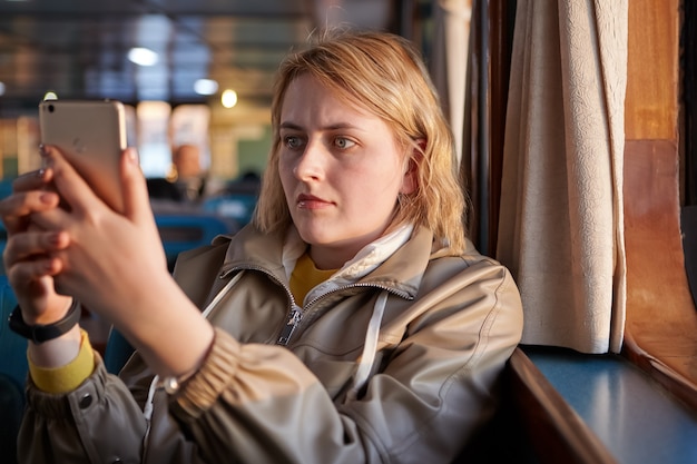 Selfie in passenger cabin of ferry young white woman with serious face takes pictures of herself