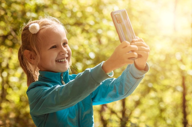 Selfie Taking Child in nature. Cute little Girl takes Selfie in Park