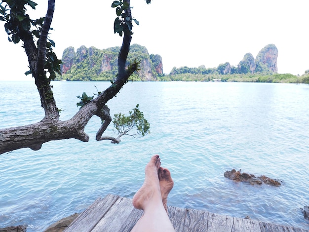 Selfie woman bare foot on wooden floor over summer beach with island background