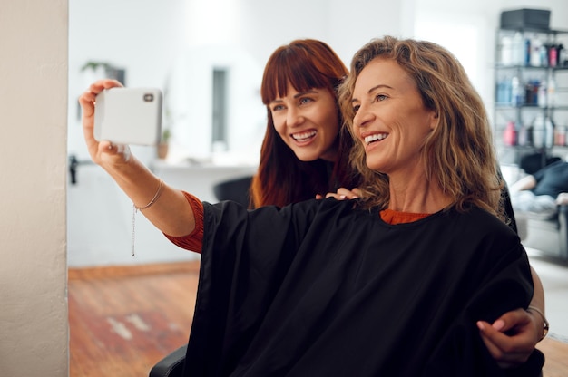 Photo selfie women and designer hairdresser spa hair care day at salon studio beauty senior customer and young hair stylist take photograph on mobile phone at successful small grooming business