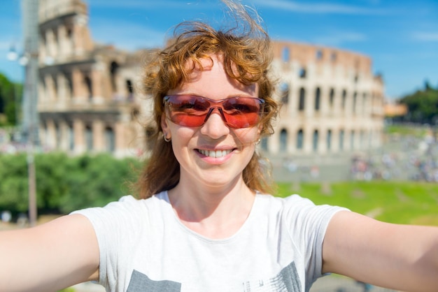 Selfie of a young female tourist on the background of the Colosseum in Rome