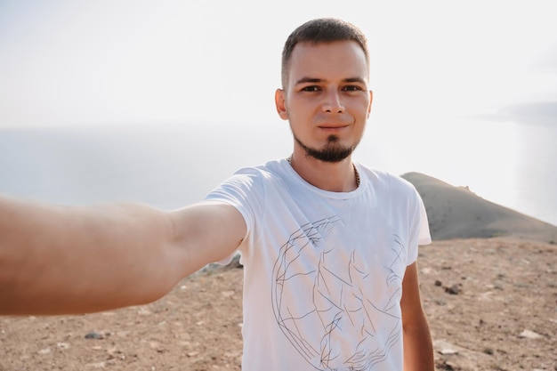 Selfieportrait of a young male tourist against the background of mountains The concept of tourism shared recreation