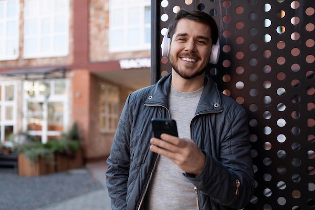 Selfsatisfied man in headphones listening to music and reading a message on a mobile phone