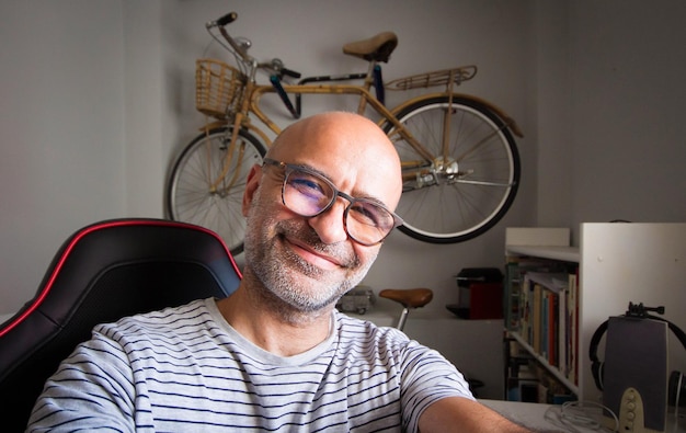 Selfy of happy bald man with glasses inside