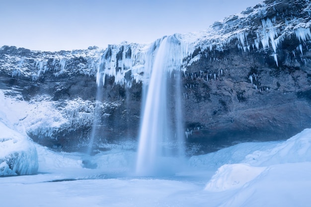 Seljalandsfoss waterfall Iceland Icelandic winter landscape High waterfall and rocks Snow and ice Powerful stream of water from the cliff A popular place to travel in Iceland