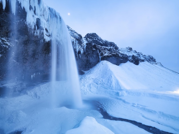 Seljalandsfoss waterfall Iceland Icelandic winter landscape High waterfall and rocks Snow and ice Powerful stream of water from the cliff A popular place to travel in Iceland