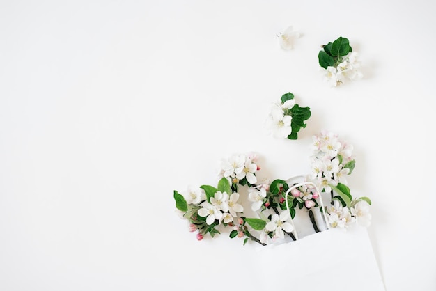 Sell concept White shopping bag on white background decorated with spring flowers apple tree