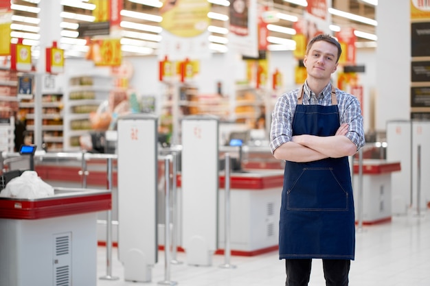 Seller in food store stands with crossed hands, copy space