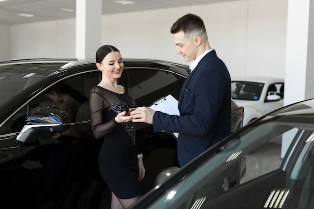 Seller gives the buyer the keys to a new car in the showroom