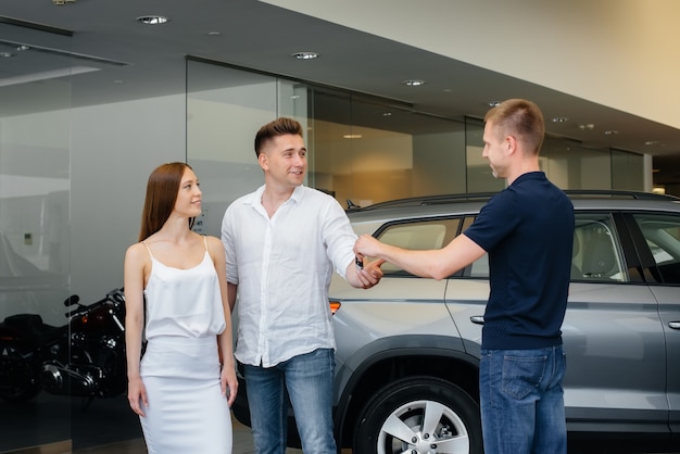 The seller passes the keys to a new car to a young family. Buying a new car.