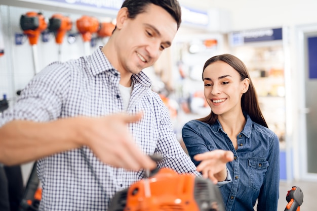 Seller in the store shows the customers a grasscutter.