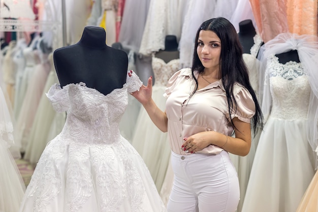 Seller in wedding salon demonstrating dresses for bride