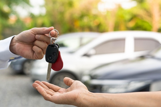 Selling car car sale deal concept The dealer gives the car keys to the new owner or renter with an insurance contract