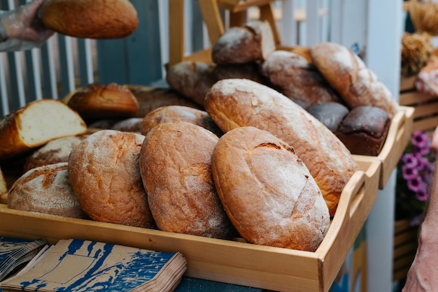 Selling freshly baked rye bread at street stall Brown rustic bread with crust and flour Closeup selective focus