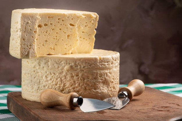 Semi-cured cheese from Brazil arranged on a rustic board on a green and white checkered tablecloth, selective focus.