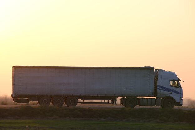 Photo semitruck with cargo trailer driving on highway hauling goods in evening delivery transportation and logistics concept