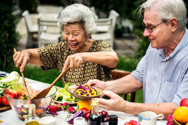 Senior adult couple sitting making salad